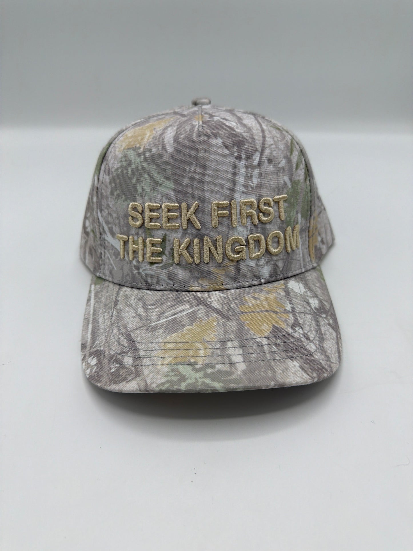 Seek First The Kingdom in cream puff embroidery on a full camo five panel snapback