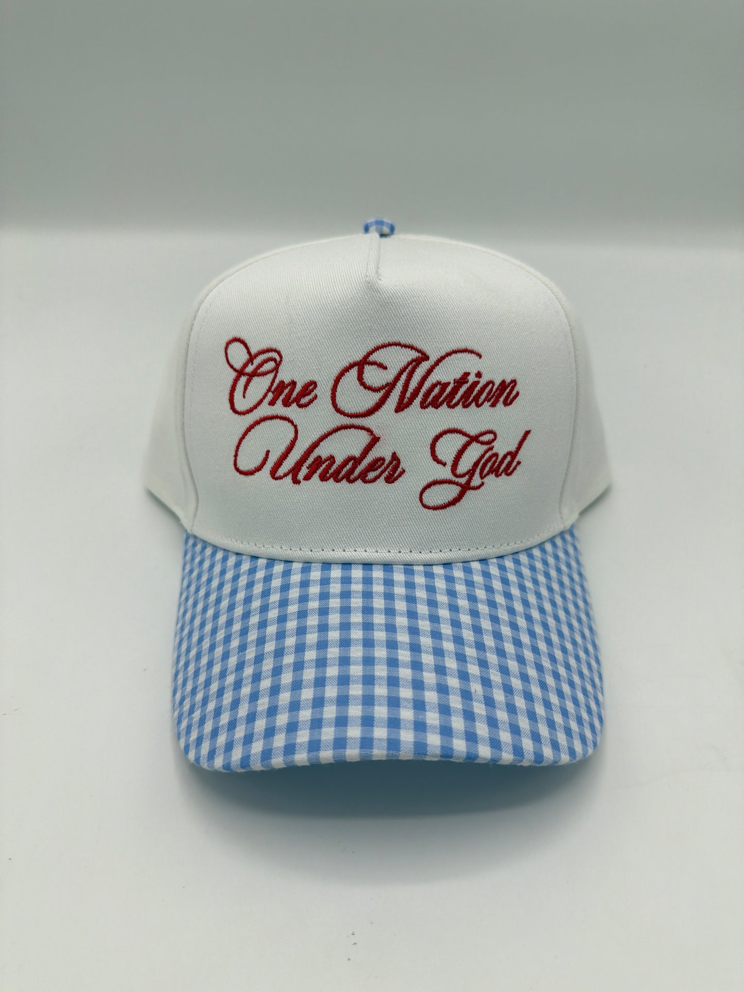 One Nation Under God embroidered in dark red script on a white crown with a blue gingham brim