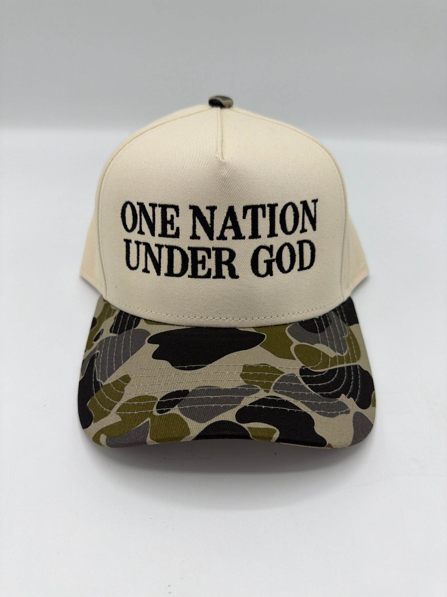 One Nation Under God embroidered in black serif on a cream crown with a duck camo brim