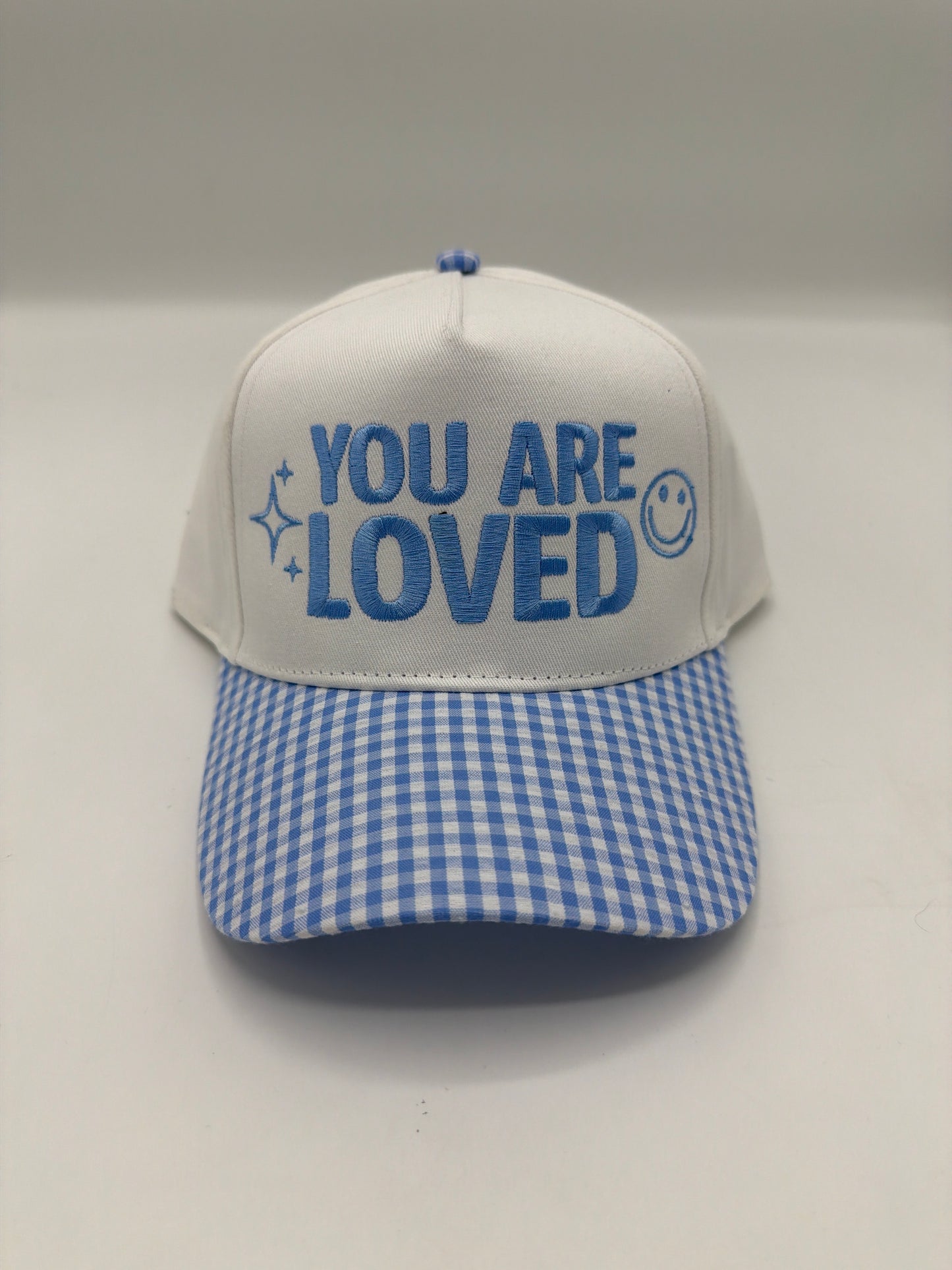 You Are Loved with a smiley and sparkles in cornflower blue on a white crown with a blue gingham brim