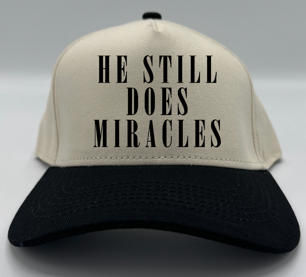 He Still Does Miracles in black embroidery on a natural crown with a black brim