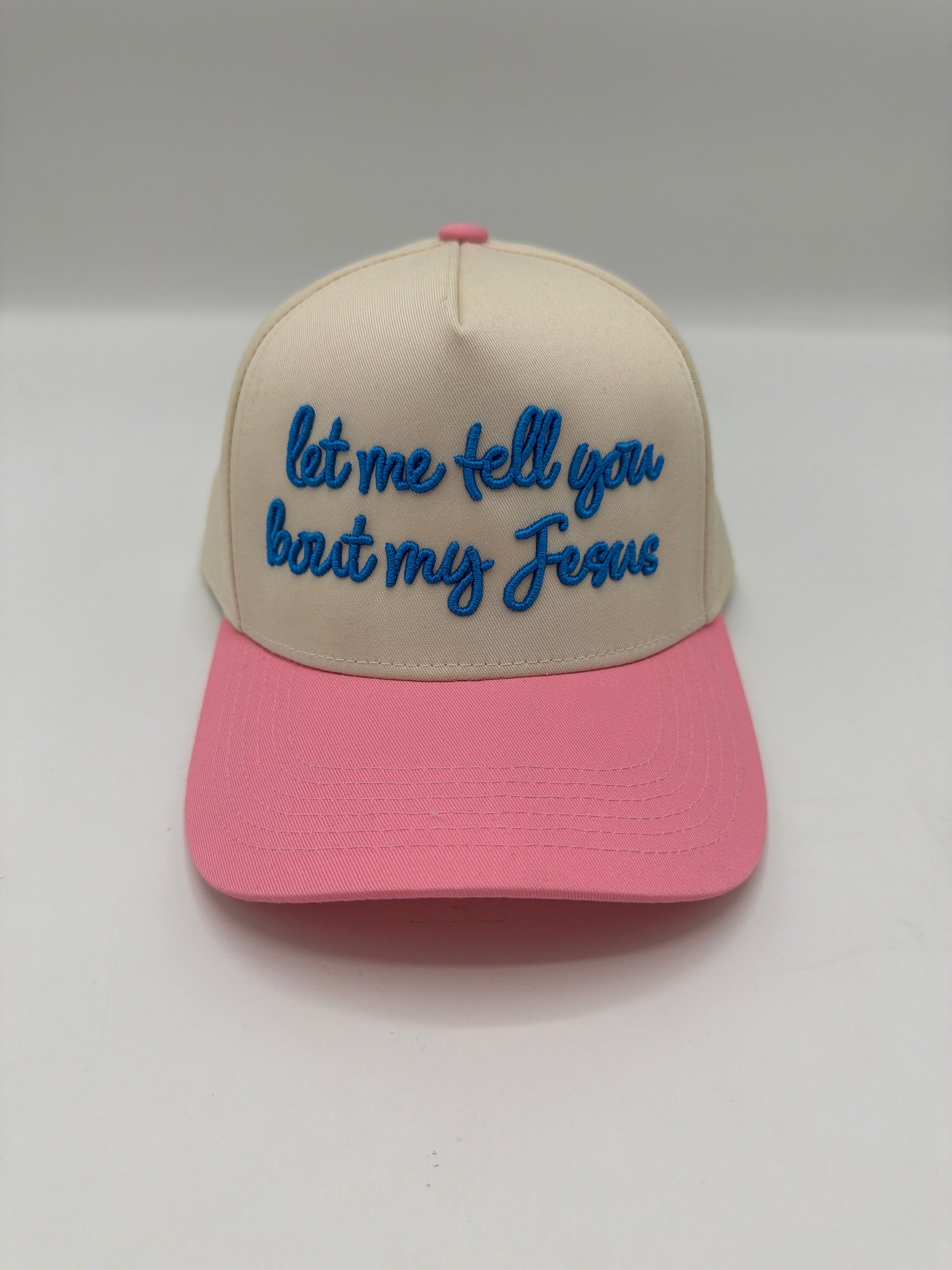 Let me tell you bout my Jesus in blue script on a cream crown with a pink brim