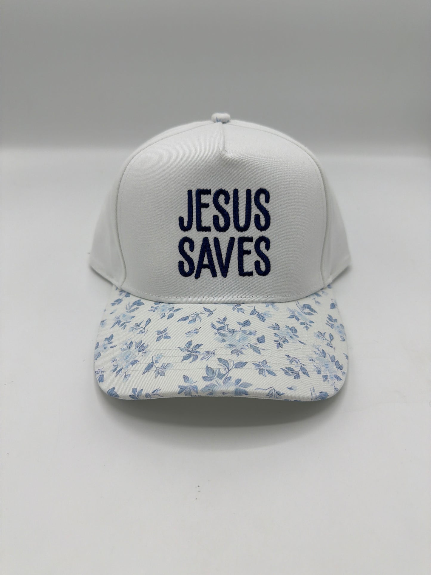 Jesus Saves in navy block embroidery on a white crown with a blue floral brim